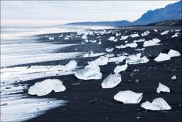 Крижана річкова лагуна з чорним піском, озеро Єкюльсаурлоун, південно-східна Ісландія. Крижані брили, подібні величезним блискучим кристалам, розкидані по верхній поверхні бухти, створюють цей чарівний пейзаж, схожий на сон. Лід потрапляє сюди з сусіднього льодовика, а причина чорного кольору піску - вулканічні породи, навколишні бухту.