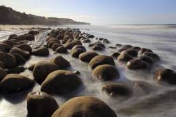 Пляж з "куль для боулінгу", Каліфорнія, США.  Великі круглі валуни, що нагадують величезні кулі для боулінгу, розкидані по березі на цьому пляжі в Скунер-Галч. Кажуть, округлі кам'яні кулі - результат мільйонів років ерозії і «конкреції», досить рідкісного геологічного феномена, які можна спостерігати також в Моєраки в Новій Зеландії і на річці Каннонболл Рівер в Північній Дакоті.